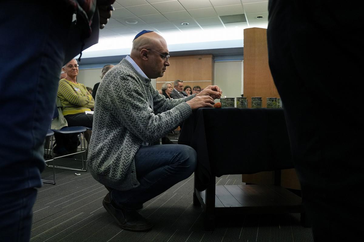 Mikhail Krasnopolskiy kneels to light a candle in memory of lives lost during the Holocaust. 学生, 教师, community members and others attended the Holocaust Commemoration Service on May 5 at South Hall Commons. Photo by Jamie Cotten / Colorado College